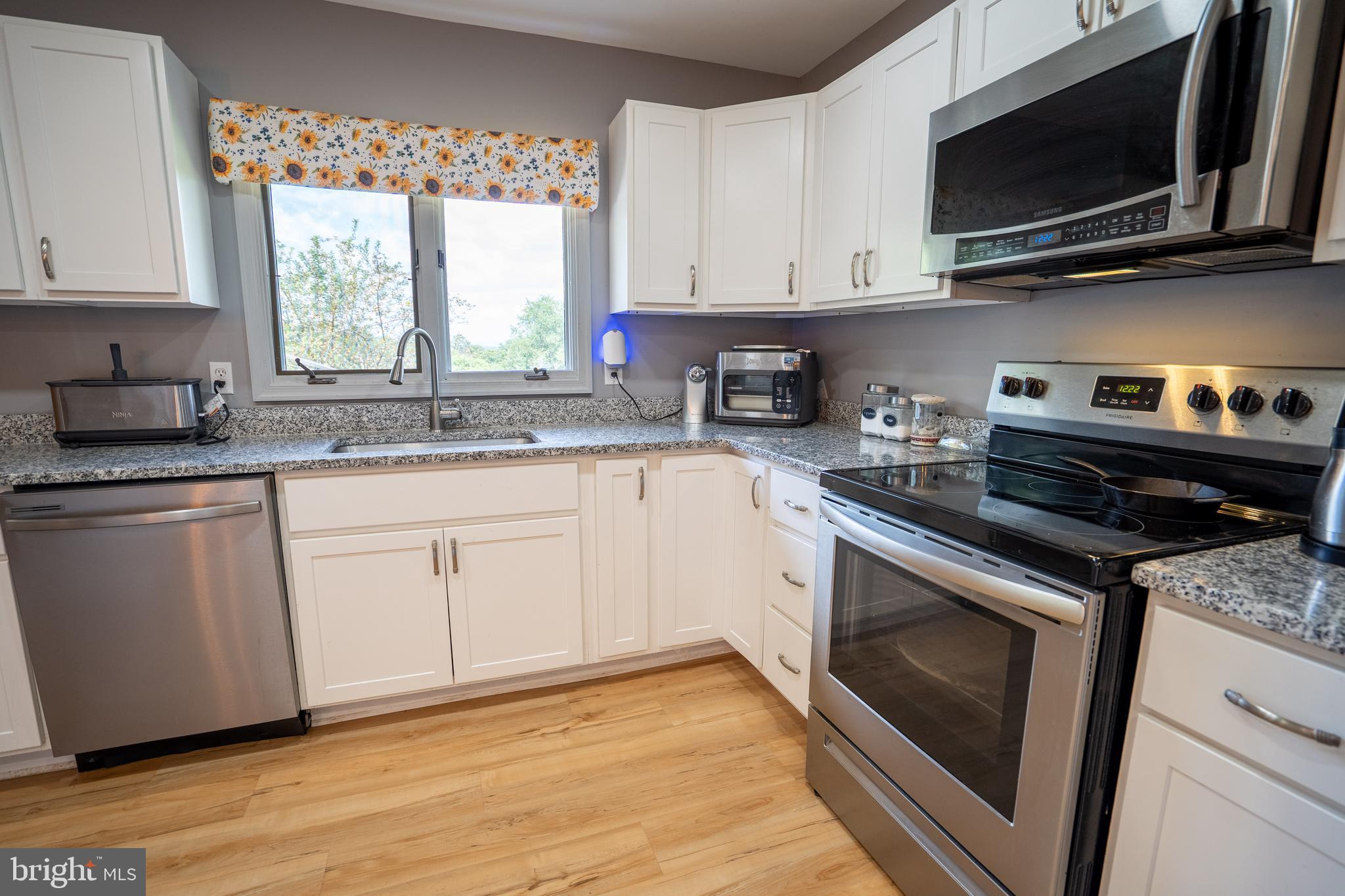 474 Potter Road Hedgesville, WV 25427 - Photo 8 of 40 a kitchen with stainless steel appliances granite countertop a sink a stove a microwave and wooden cabinets