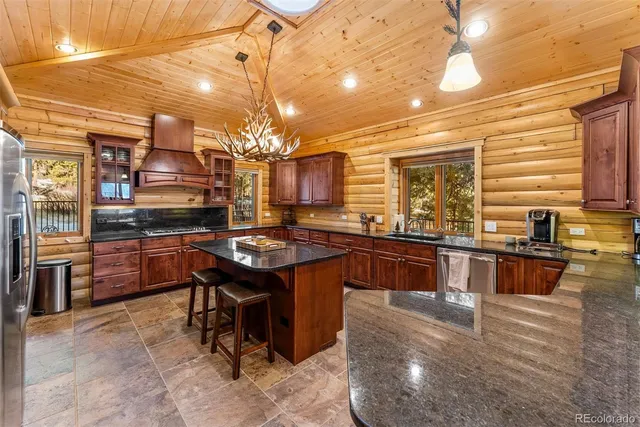 a kitchen with stainless steel appliances granite countertop a sink a stove and a wooden cabinets