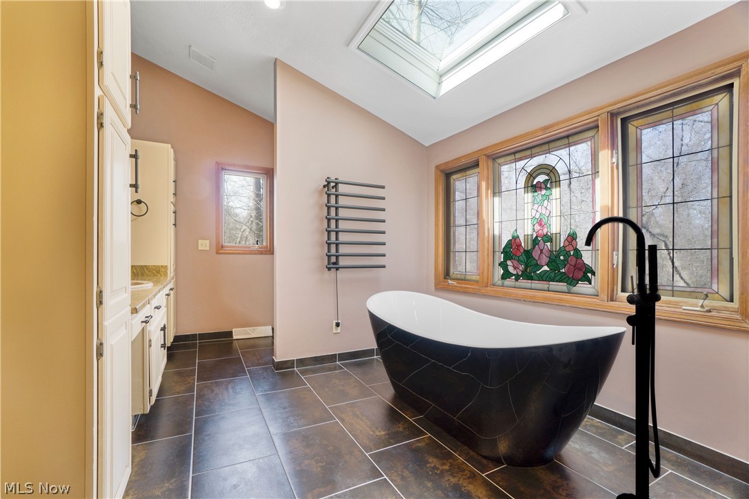 29329 Eddy Road Wickliffe, OH 44092 - Photo 24 of 50 Bathroom with vaulted ceiling with skylight, tile floors, vanity, and a washtub