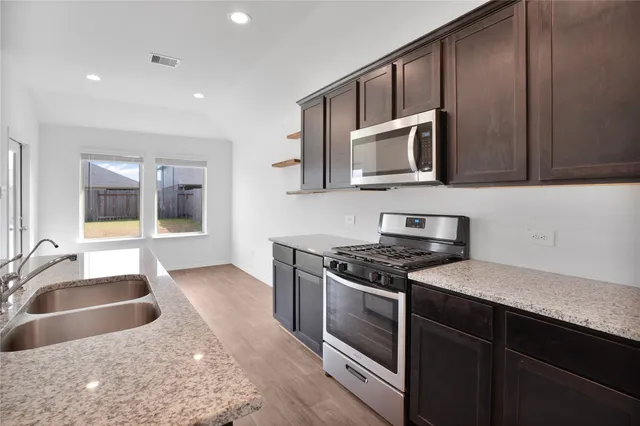 a kitchen with stainless steel appliances granite countertop a sink stove and microwave