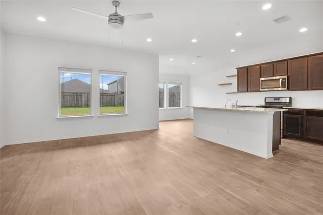 a large kitchen with stainless steel appliances granite countertop a stove top oven a sink and a microwave