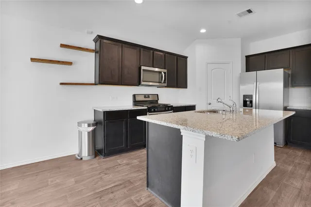 a kitchen with stainless steel appliances granite countertop a sink stove and refrigerator