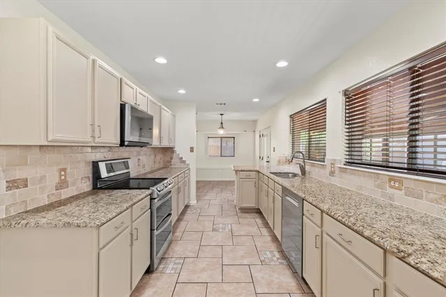 a large kitchen with stainless steel appliances granite countertop a lot of counter space and a sink