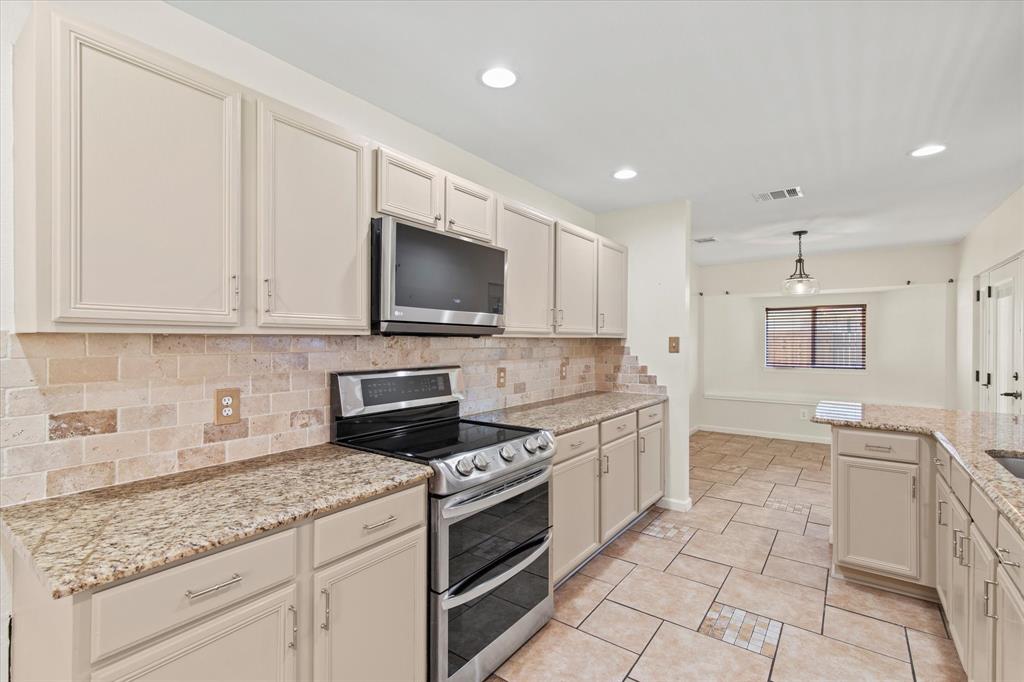 2201 Driskell Lane Corinth, TX 76210 - Photo 13 of 40 a kitchen with granite countertop a sink a stove top oven and cabinetry