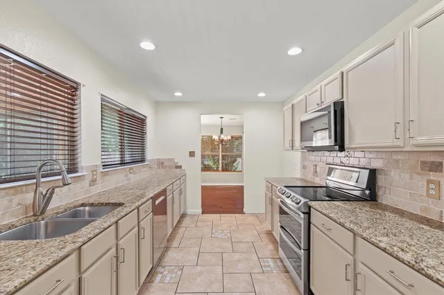 a kitchen with granite countertop a sink stove and cabinets