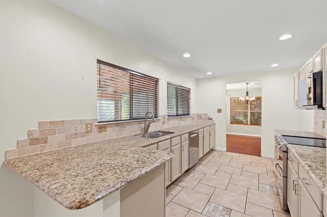 a large white kitchen with granite countertop a large counter top and sink