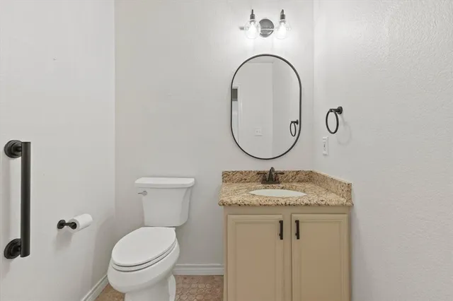 a bathroom with a granite countertop toilet a sink and a mirror