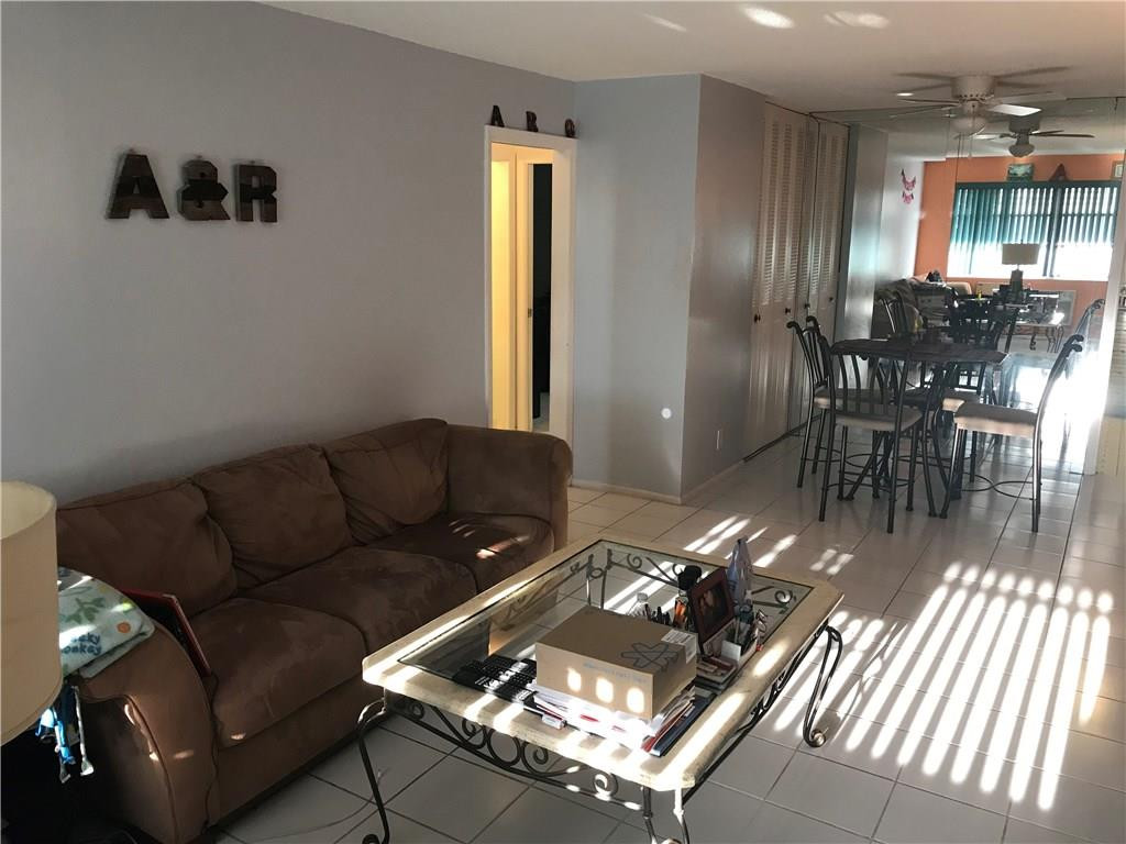 1150 East Sample Road, Unit 201 Pompano Beach, FL 33064 - Photo 3 of 8 a living room with patio furniture and a chandelier