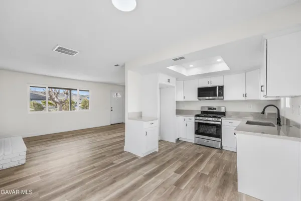 a kitchen with stainless steel appliances a stove top oven a sink a refrigerator a window
