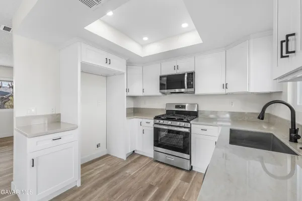 a kitchen with stainless steel appliances white cabinets a sink a stove a refrigerator and microwave