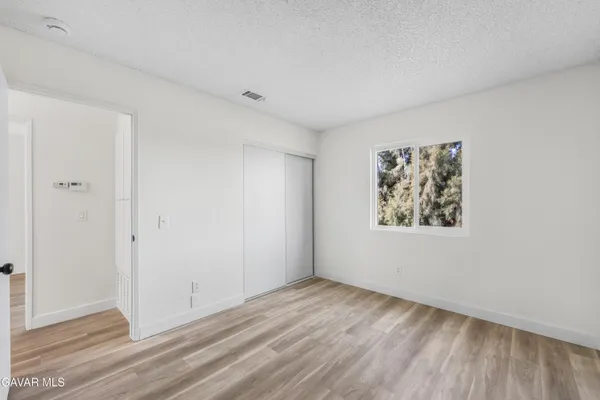 a view of an empty room with wooden floor and closet