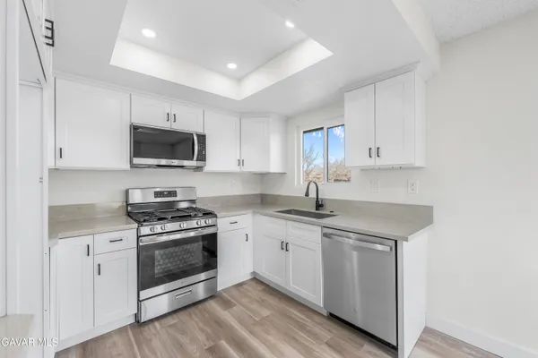 a kitchen with stainless steel appliances granite countertop a stove top oven a sink and white cabinets