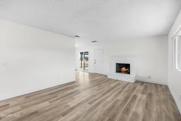 a view of empty room with wooden floor and fireplace