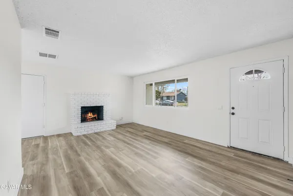 a view of an empty room with wooden floor and a fireplace