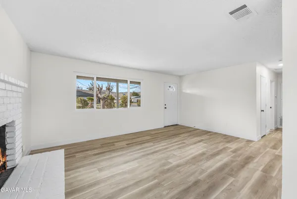 a view of an empty room with window and wooden floor