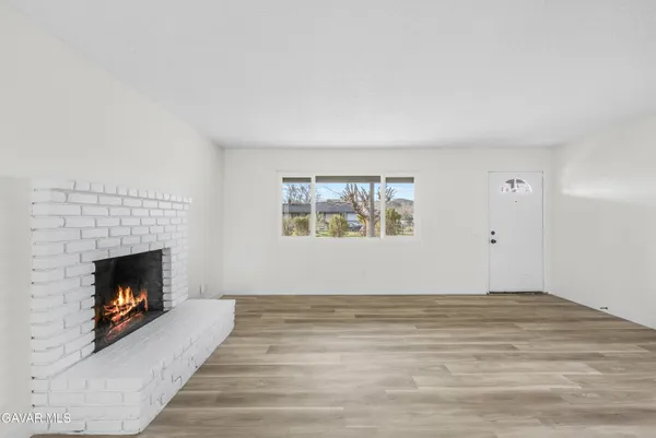a view of an empty room with a fireplace and wooden floor