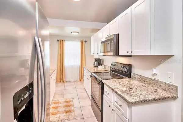 a kitchen with stainless steel appliances granite countertop a refrigerator a stove and a sink