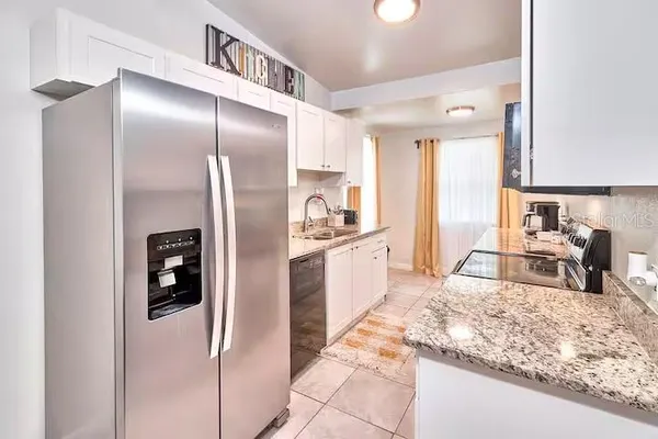 a kitchen with granite countertop a sink a stove top oven and cabinetry