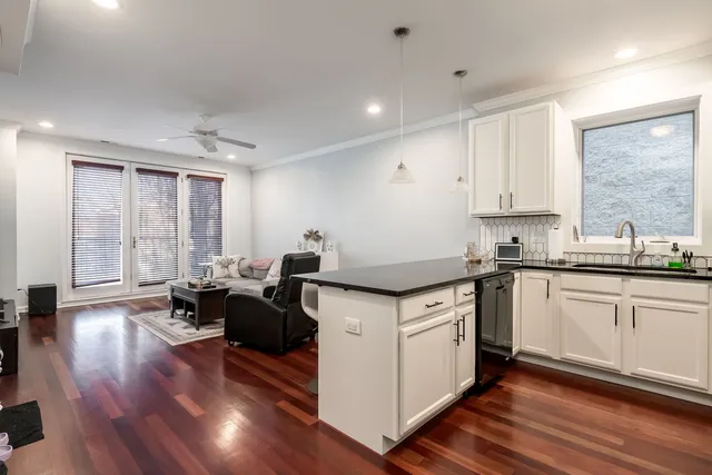 a kitchen with granite countertop a stove a sink a refrigerator and white cabinets with wooden floor