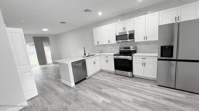 a kitchen with white cabinets and stainless steel appliances