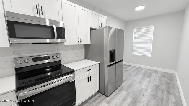 a kitchen with stainless steel appliances a stove a microwave and a hard wood floors
