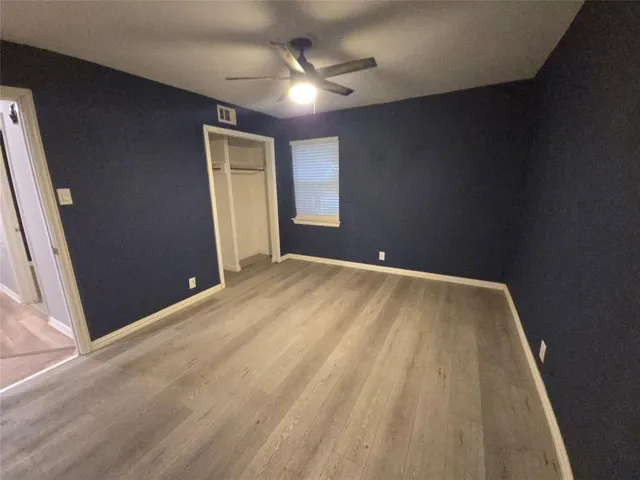 an empty room with closet and a ceiling fan