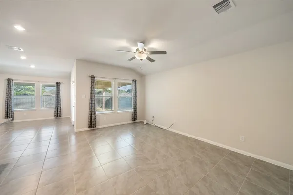 an empty room with chandelier fan and windows