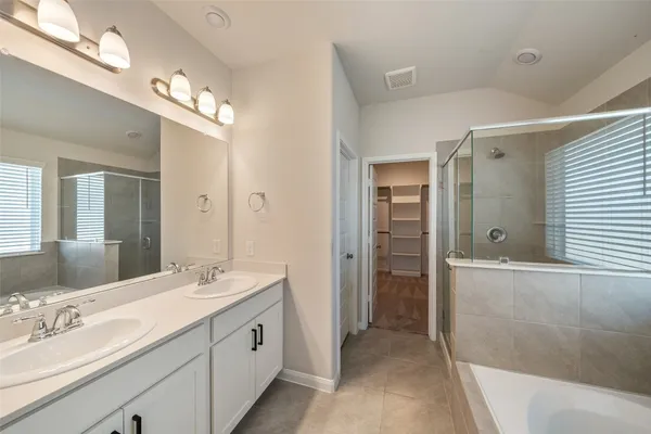 a spacious bathroom with a double vanity sink a large mirror and a shower