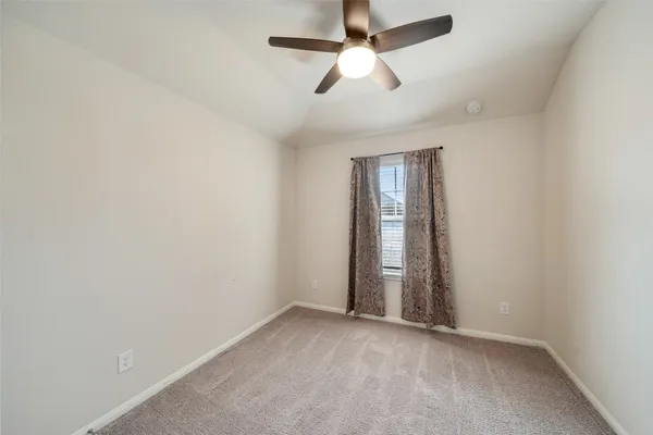 an empty room with a window and ceiling fan