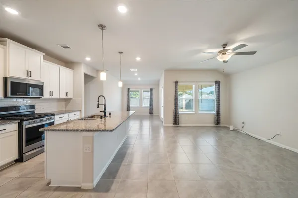 a large kitchen with stainless steel appliances kitchen island granite countertop a stove a sink a window and cabinets