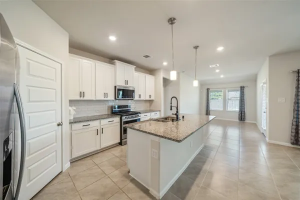 a large white kitchen with stainless steel appliances granite countertop a stove oven and a refrigerator