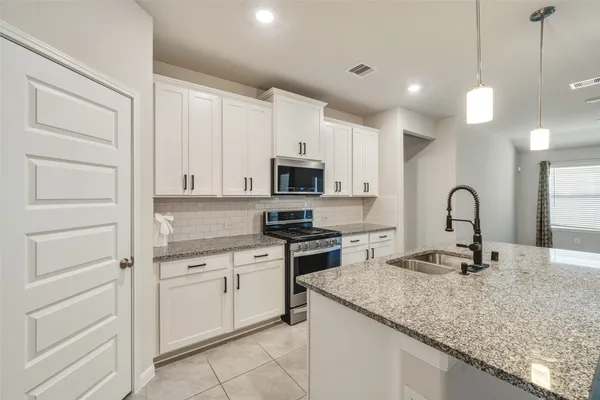 a kitchen with granite countertop white cabinets and stainless steel appliances