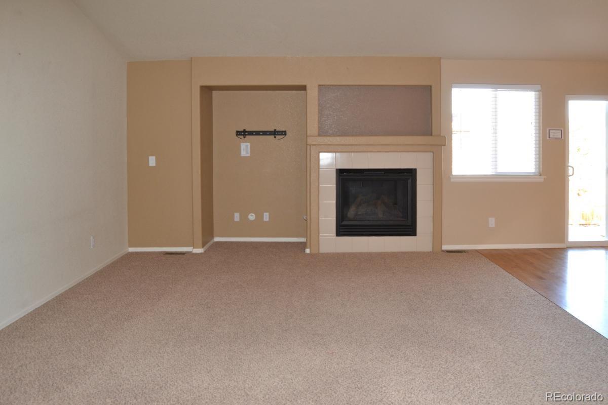 8039 Raspberry Drive Frederick, CO 80504 - Photo 12 of 28 an empty room with a fireplace and windows