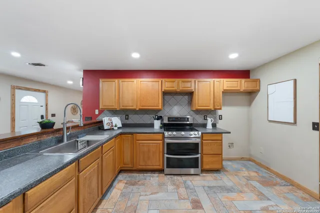 a large kitchen with stainless steel appliances granite countertop a stove a sink and a refrigerator