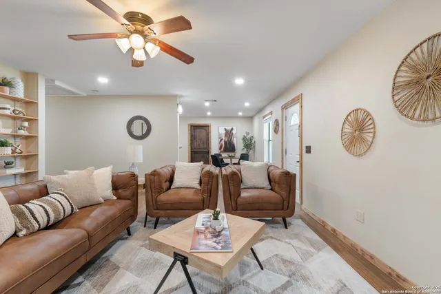 a living room with furniture a clock and a ceiling fan