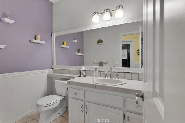 a bathroom with a granite countertop sink a toilet and a mirror