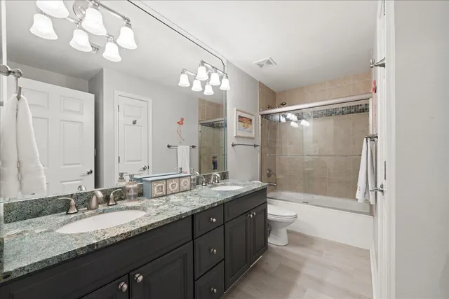 a bathroom with a granite countertop sink a toilet a mirror and shower