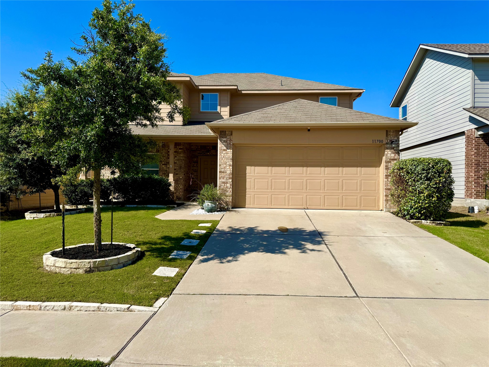 A welcoming home presents an attached garage and well-maintained lawn with mature landscaping.