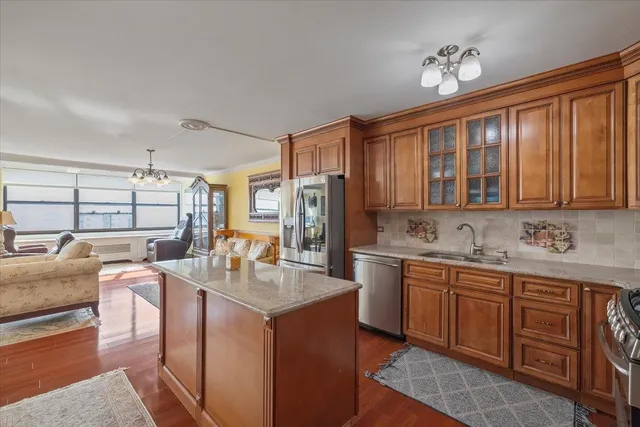 a kitchen with stainless steel appliances granite countertop a sink dishwasher stove and refrigerator with wooden cabinets