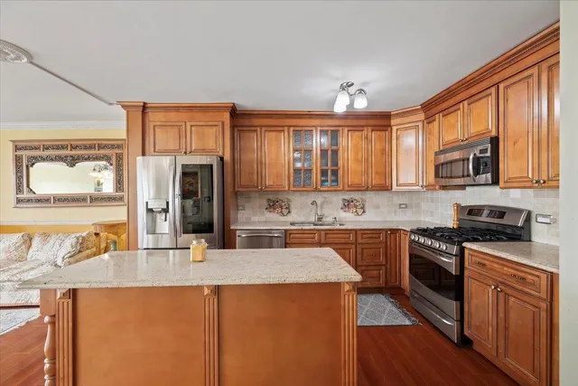 a kitchen with stainless steel appliances granite countertop a sink dishwasher stove and refrigerator with wooden cabinets