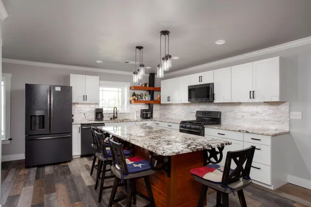 a kitchen with stainless steel appliances granite countertop a dining table chairs microwave and refrigerator