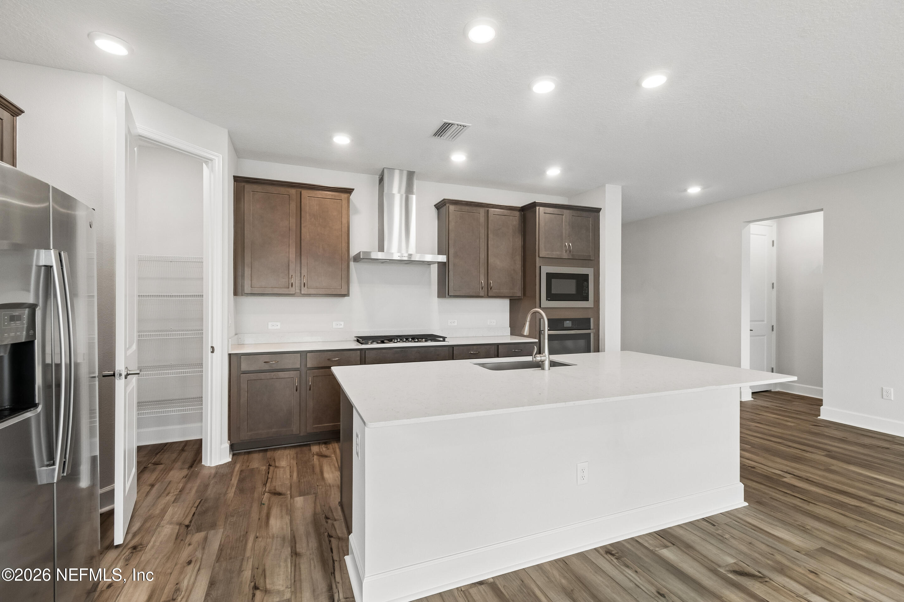 75751 Bayley Place Yulee, FL 32097 - Photo 6 of 28 a large kitchen with stainless steel appliances granite countertop a stove a refrigerator a sink and a oven with wooden floor