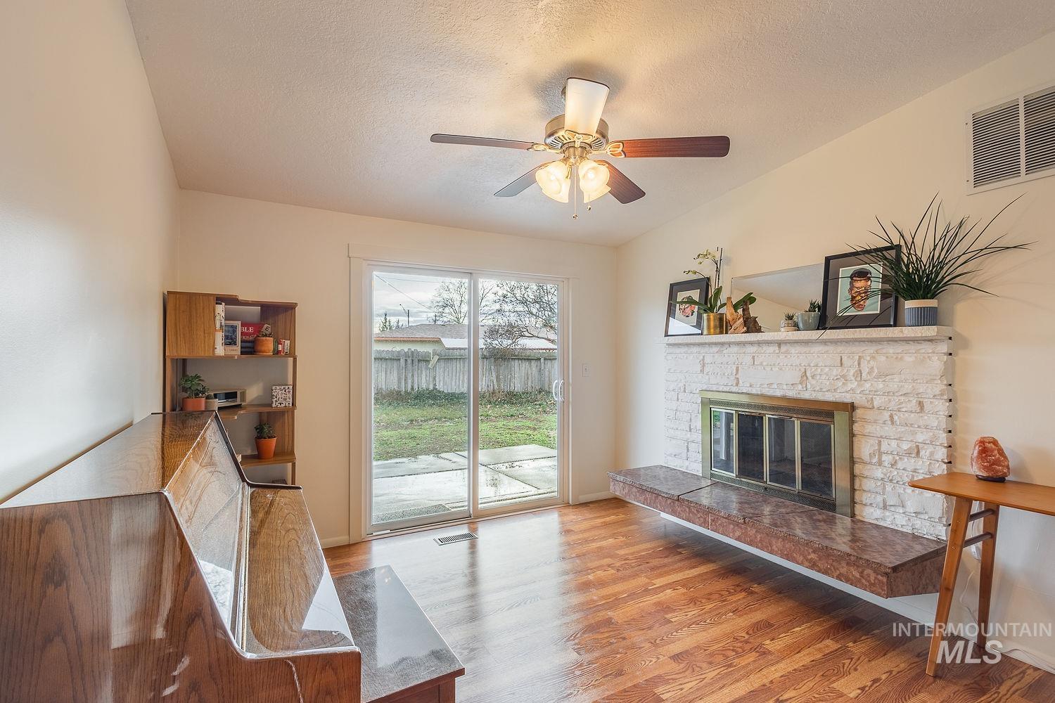 6403 Colonial Drive Boise, ID 83709 - Photo 12 of 42 Living area featuring a textured ceiling, a fireplace, light wood-type flooring, and a ceiling fan