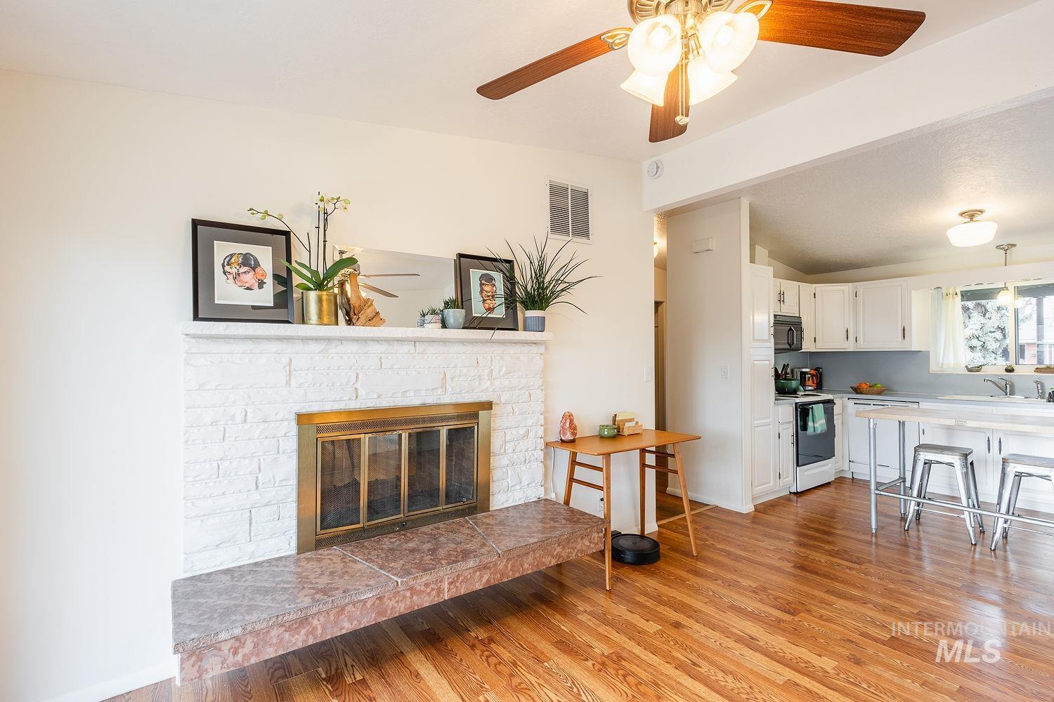 6403 Colonial Drive Boise, ID 83709 - Photo 14 of 42 Living room with a ceiling fan, a glass covered fireplace, light wood-style floors, and vaulted ceiling