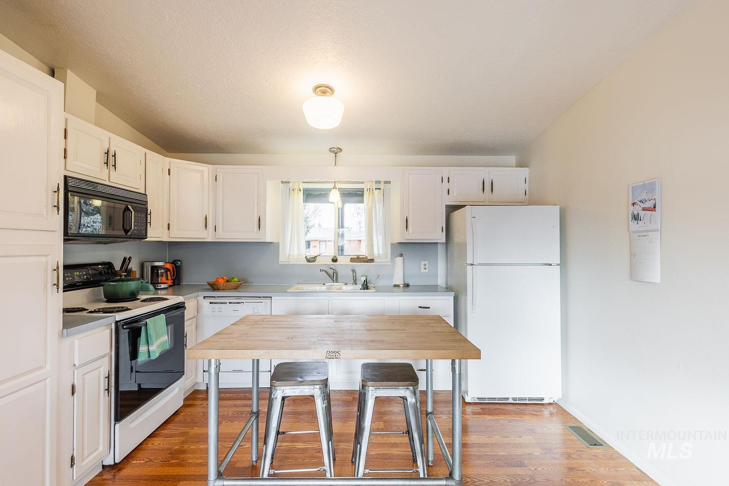 6403 Colonial Drive Boise, ID 83709 - Photo 16 of 42 Kitchen featuring white appliances, white cabinetry, light countertops, light wood-style flooring, and a textured ceiling