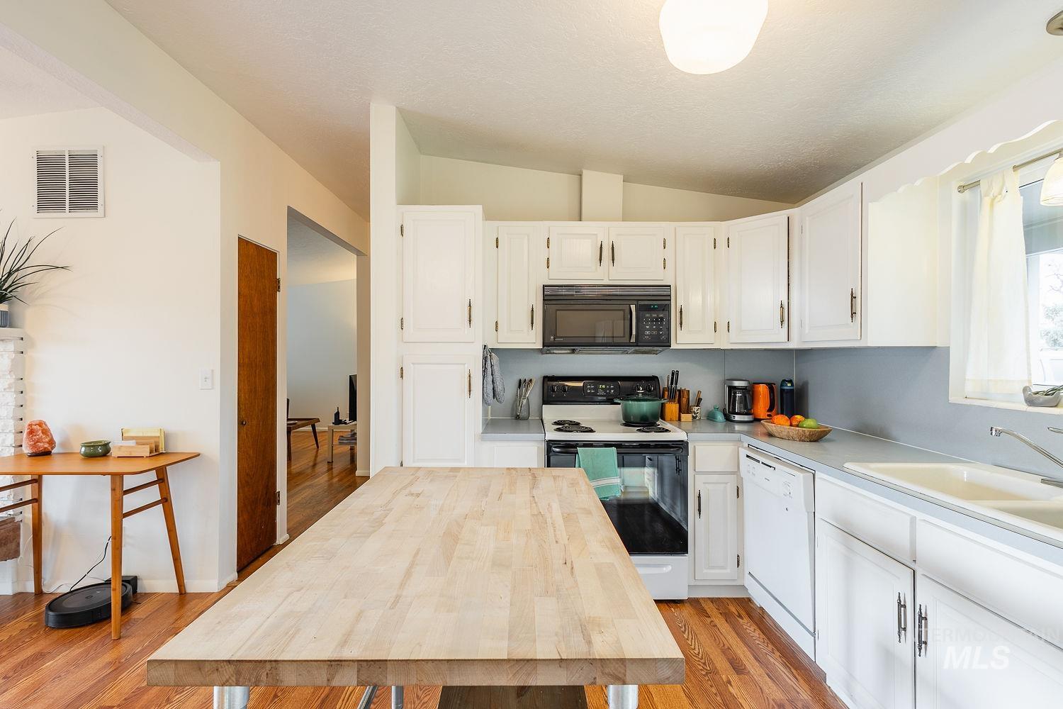 6403 Colonial Drive Boise, ID 83709 - Photo 19 of 42 Kitchen with range with electric cooktop, black microwave, white cabinetry, lofted ceiling, and white dishwasher