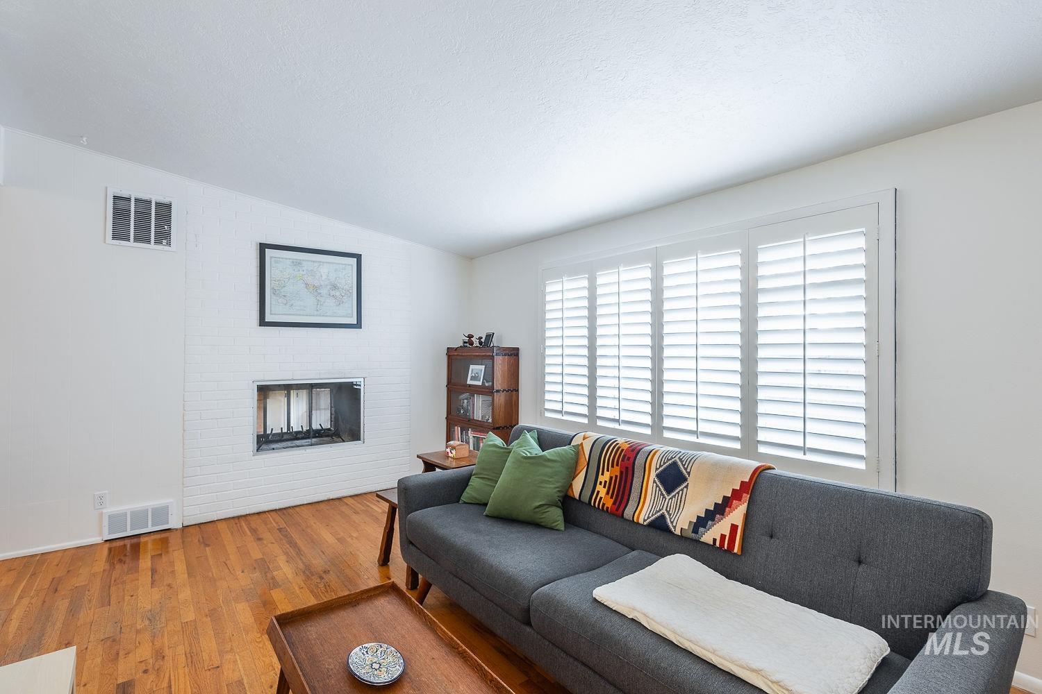 6403 Colonial Drive Boise, ID 83709 - Photo 8 of 42 Living room with wood finished floors, vaulted ceiling, a textured ceiling, and a brick fireplace