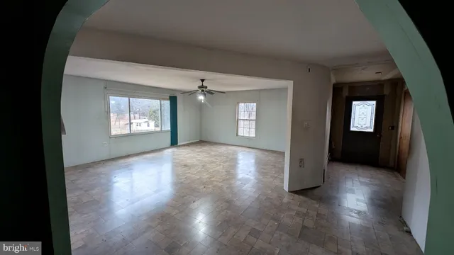 an empty room with wooden floor windows and fireplace