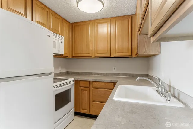 a kitchen with granite countertop a sink a stove and cabinets