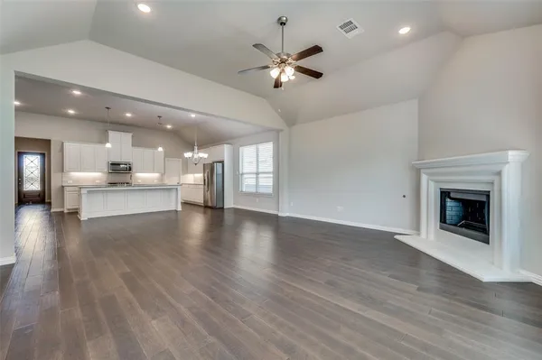a view of an empty room with a fireplace and wooden floor